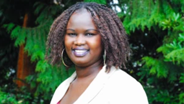 Smiling woman in front of green foliage.