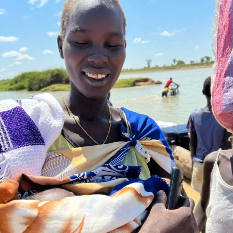 Smiling woman holding colorful fabric outdoors.