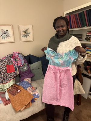 Woman holding a colorful dress, smiling in a cozy living room.