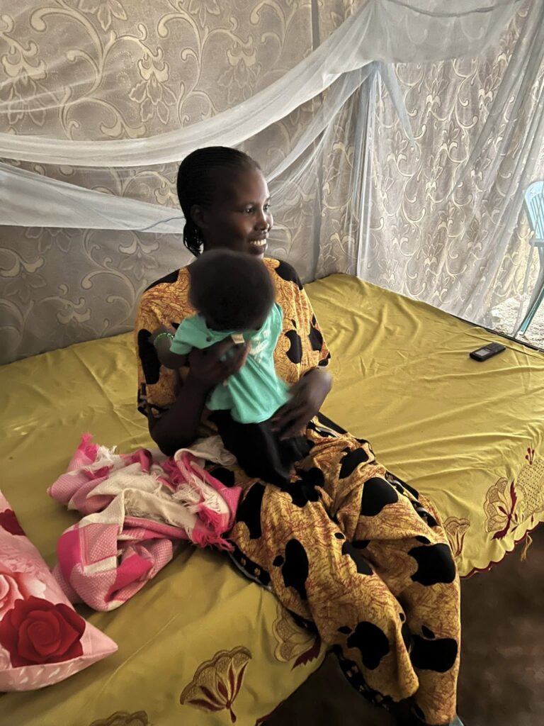A woman breastfeeding a baby on a yellow bed.